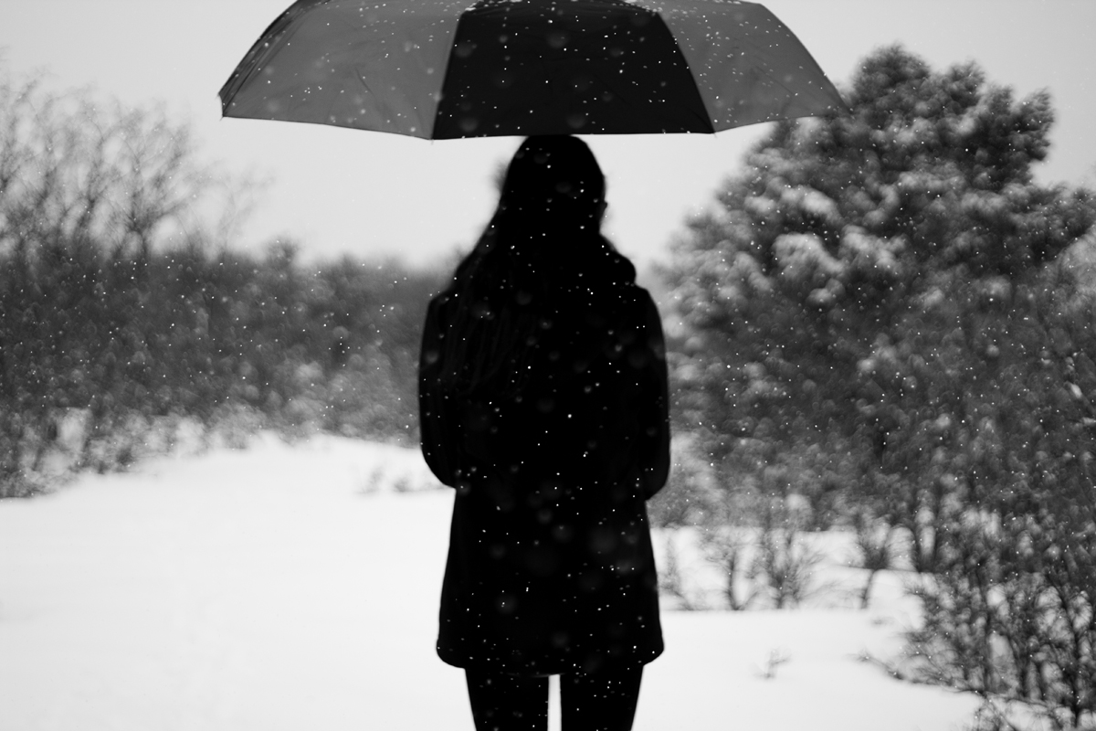A female holding an umbrella while snow falls